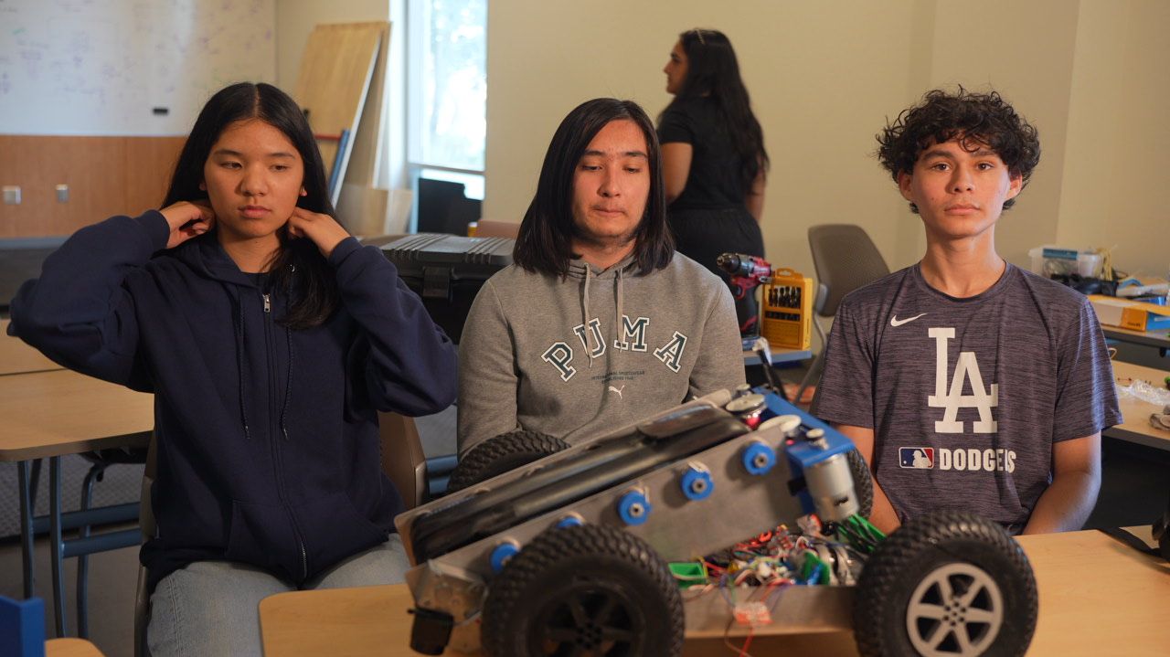 Three students posing with their finished robot