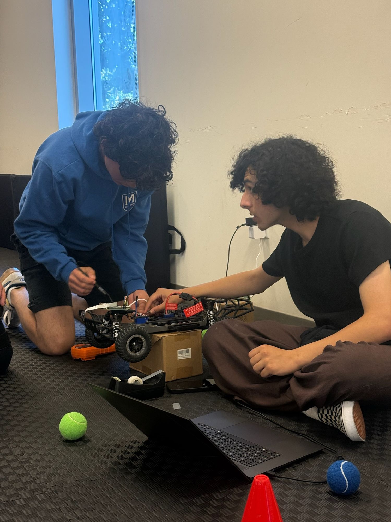 Two students wiring an off-road robot chassis