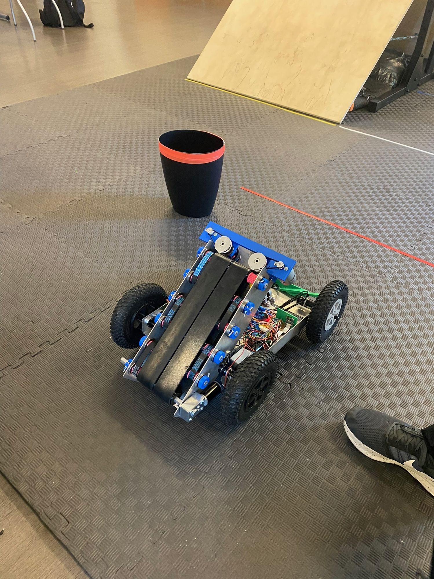 A student-built robot with a conveyor intake on a test course